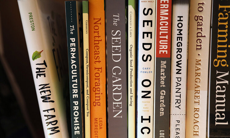 Books on seeds and gardening lined up on a shelf.